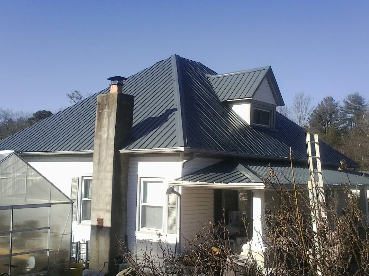 Dark blue standing seam metal roof on a white farmhouse with dormer — Slate & Tile Roof Repair by Roofing Brothers in Dunn Loring