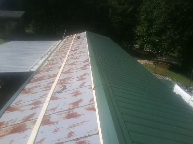 Old rusted panels beside newly installed green metal roofing — Wind Damage Roof Repair by Roofing Brothers in Dunn Loring