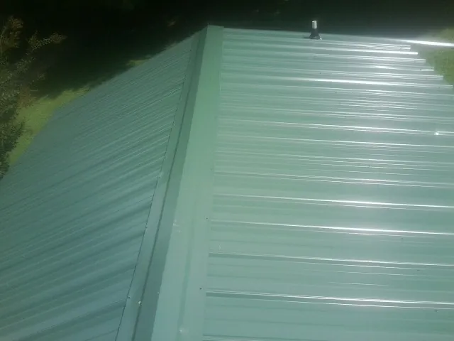 New green metal panels meeting at the ridge of a roof — Flat Roof Repair work by our crew in Dunn Loring