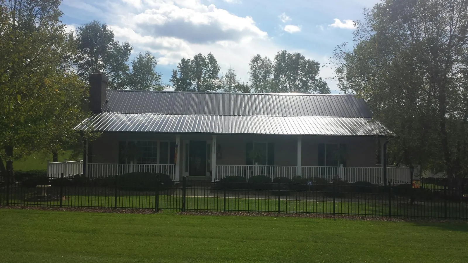 Gray metal roof on a brick ranch with a full width front porch — Gutter Guard Installation work by our crew in Dunn Loring