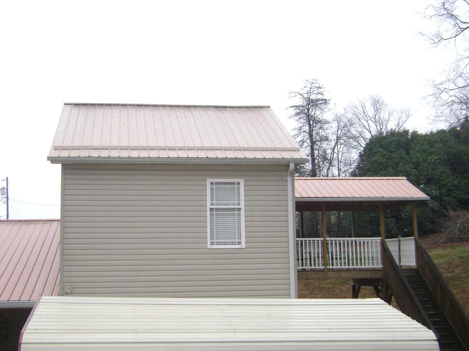 Tan metal roofs on a two story addition and attached porch, from a Roof Replacement job in Dunn Loring