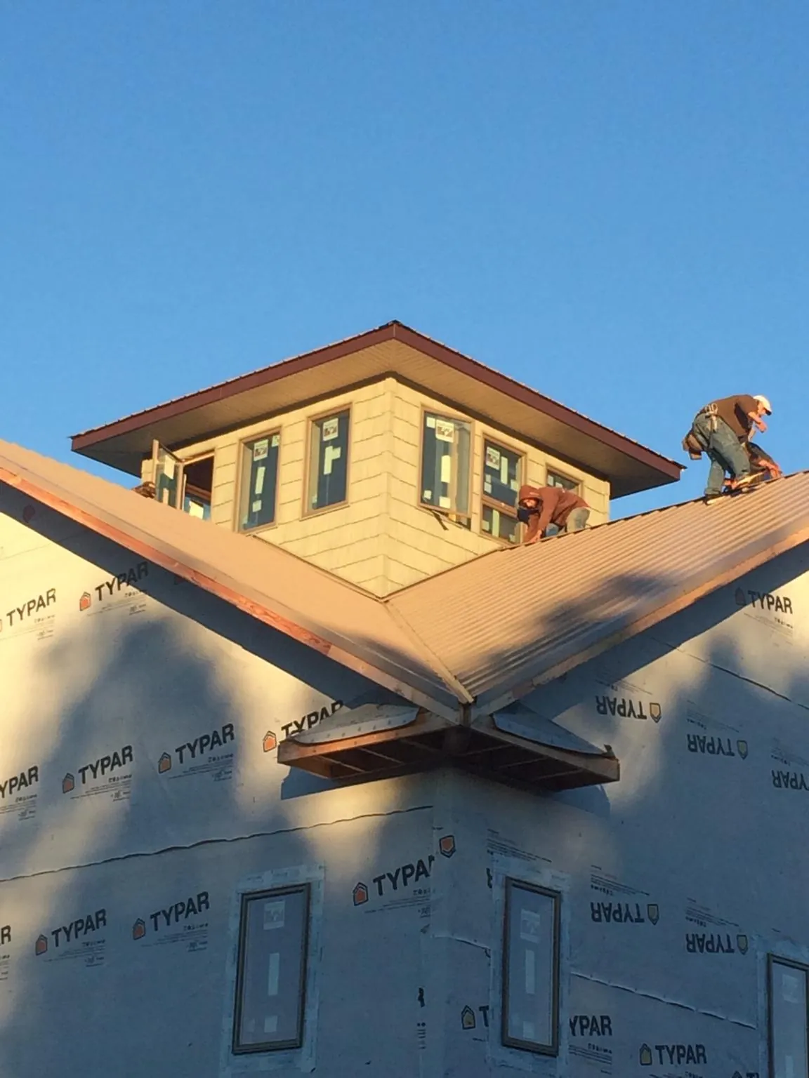 Roofers working around a rooftop cupola on a new metal roof at sunset — Roof Waterproofing in Dunn Loring by Roofing Brothers